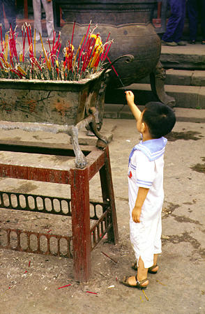Young boy lights incense in Chengdu. China.