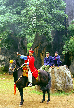 Child having portrait taken in traditional dress on horseback in stone forest near Kunming. China.