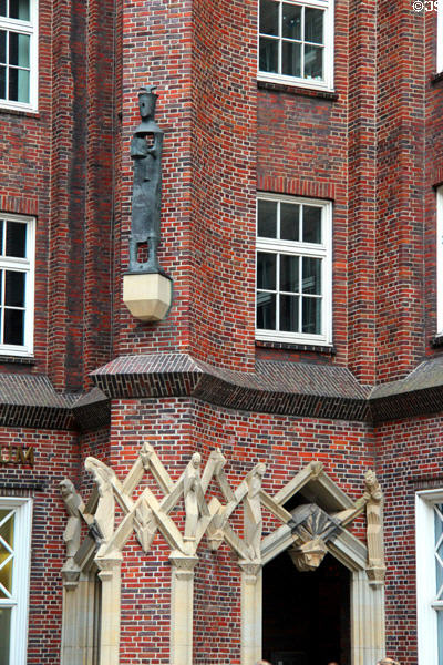 Sculpted figures held in zigzag framework with Enigma Variation figure above on Messberghof. Hamburg, Germany.