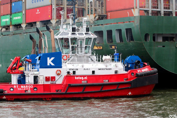 Tug boat nudging container ship into place at container port. Hamburg, Germany.