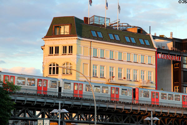 Subway train passes yellow building where Ditmar-Koel-Straße meets Elbe River. Hamburg, Germany.