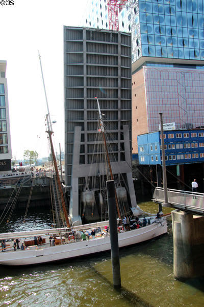 Sailing ship on Elbe River passing though lift bridge in front of Elbphilharmonie in HafenCity. Hamburg, Germany.