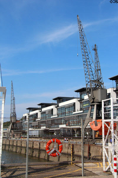 Antique cranes kept as highlight to modern buildings along Elbe River. Hamburg, Germany.