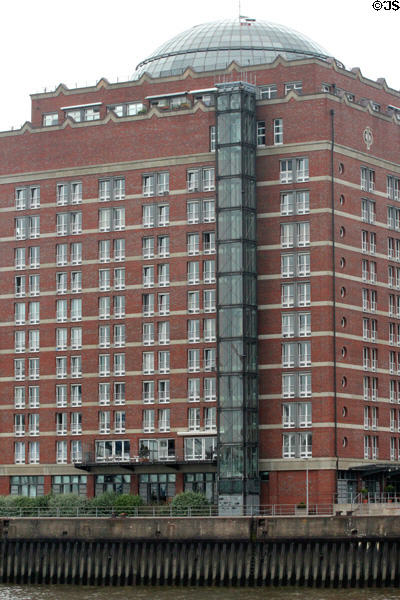 Modern brick residential building with glass dome & exterior elevator overlooking Elbe River in Altona borough. Hamburg, Germany.