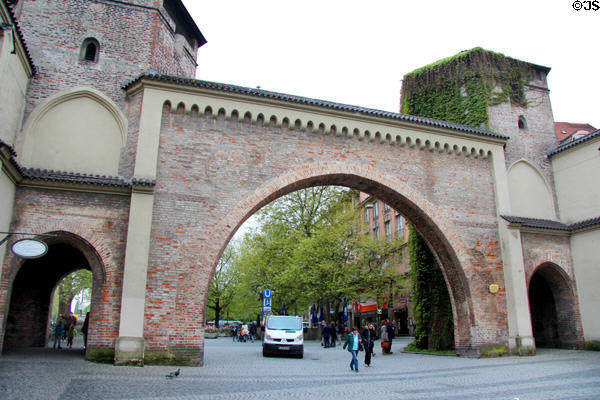 Sendling Tor restored brick gate (14thC) with 2 hexagonal towers, opening onto an Old Town plaza with a fountain. Munich, Germany.