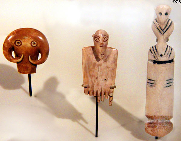 Egyptian predynastic bone amulets (4300-3050 BCE) of bull's head, comb with head of man & figure at Neues Museum. Berlin, Germany.