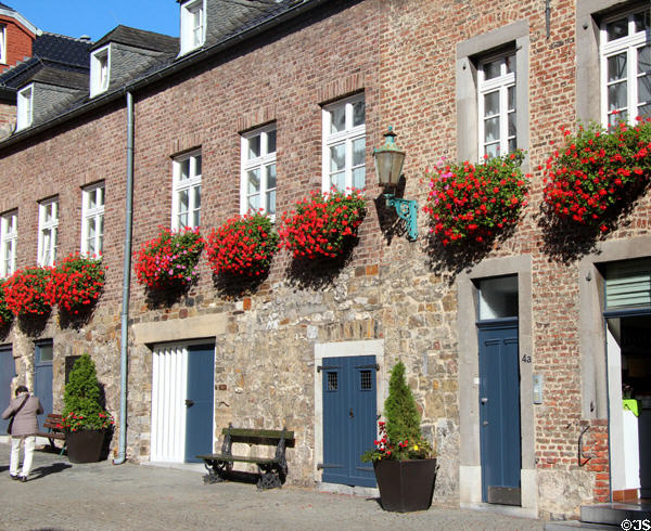 Brick row houses with flowers on Domhof at Aachen Cathedral. Aachen, Germany.