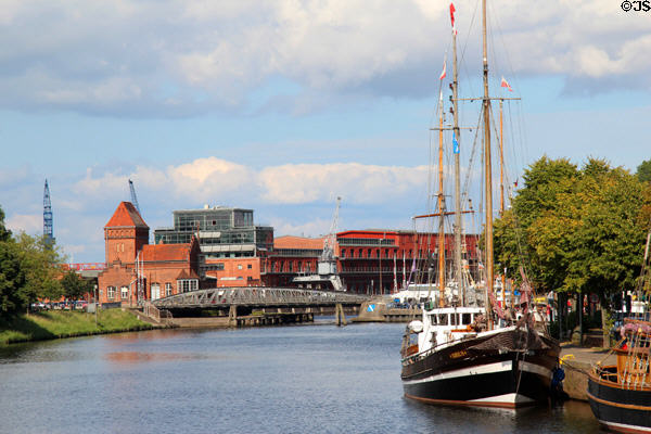 Sailing ship docked on Trave River before harbor buildings. Lübeck, Germany.