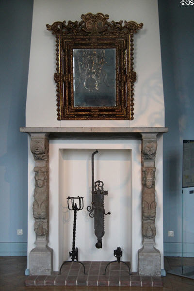 Mirror over carved fireplace mantle with andirons & adjustable pot hanger in Blue Hall at Gottorf Palace. Schleswig, Germany.