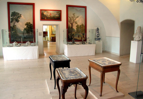 Gallery with faience (18th-19thC) made in Schleswig including small serving tables with ceramic tops at Schleswig Holstein State Museum. Schleswig, Germany.