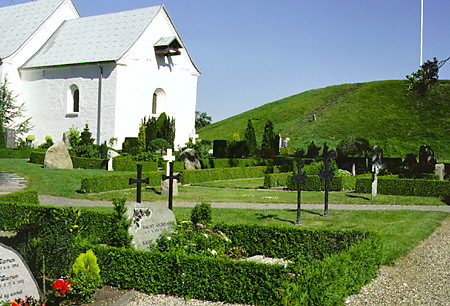 Church between ancient burial mounds and runic stones in Jelling. Denmark.