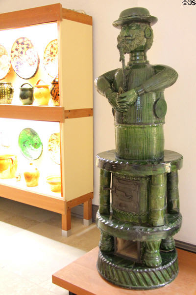 Green glazed earthenware heating oven in form of man smoking pipe (1880s) from Kröning at Bavarian National Museum. Munich, Germany.