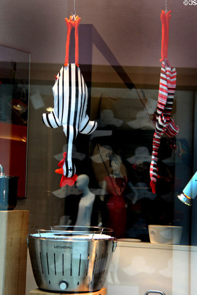 Fanciful shop window showcasing stuffed chickens over portable charcoal grill. Augsburg, Germany.
