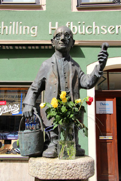 Statue of small man with bucket outside shop. Coburg, Germany.