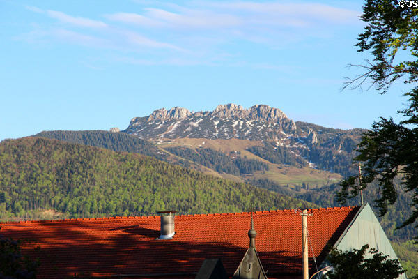Building with red tiled roof with mountain cliffs in background in Chiemsee region. Chiemsee, Germany.