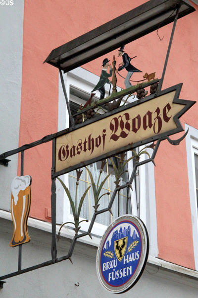 Ornate metal work of two men in top hats & dog hanging from Brau Haus Füssen. Füssen, Germany.