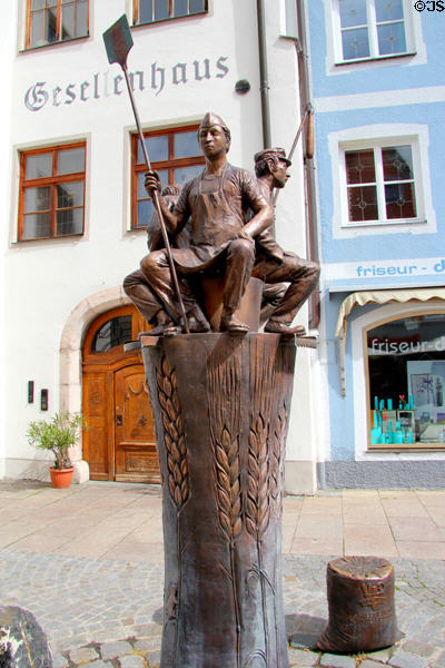 Brotbrunnen fountain with figures of bakery workers & wheat sheaves carved on pedestal on Schrannengasse in town center. Füssen, Germany.