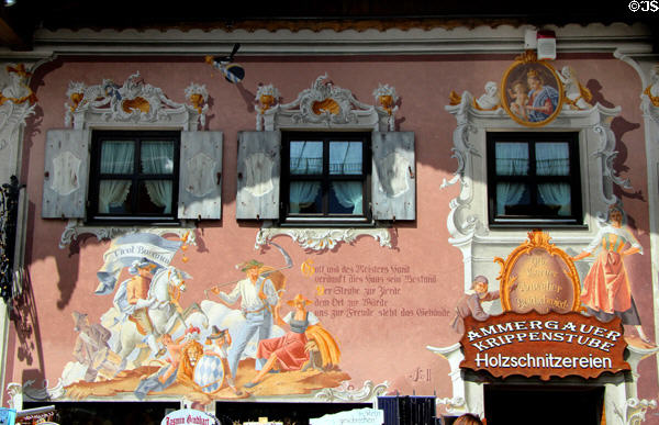 Building with decorative wooden sign for woodworker's shop & large mural on front facade. Oberammergau, Germany.
