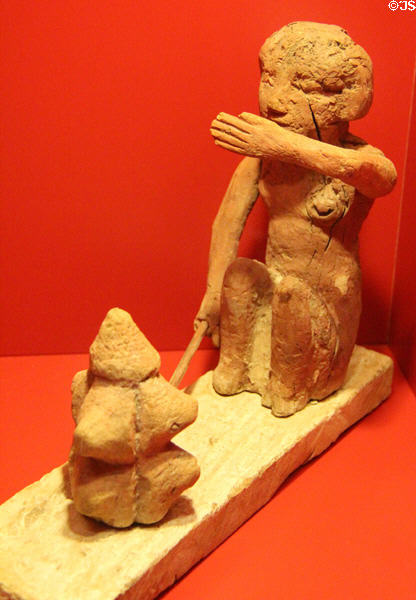 Egyptian sculpture (3rdC BCE) depicting woman baking bread by placing dough in heated clay mold on glowing charcoal at Museum of Bread and Art. Ulm, Germany.