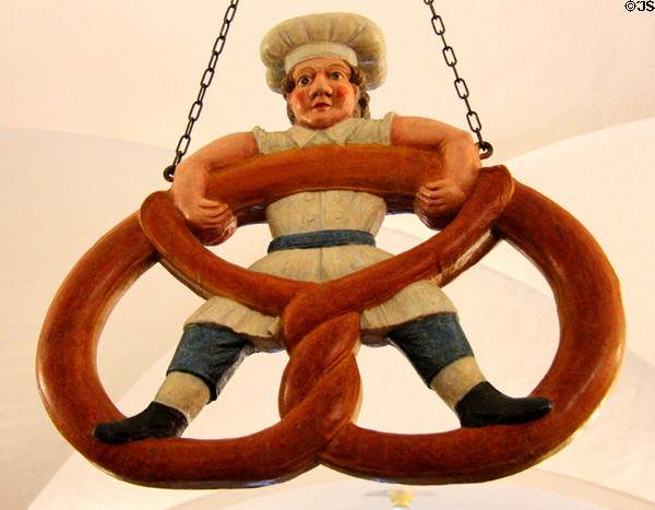 Shop sign of baker boy balancing on a pretzel at Museum of Bread and Art. Ulm, Germany.