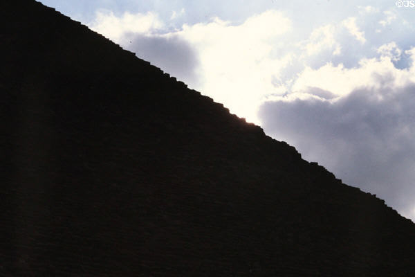 Pyramid of Cheops silhouette shows blocks along edge. Giza, Egypt.
