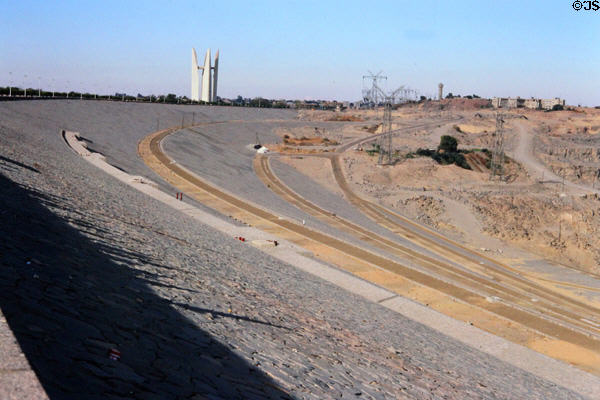 Walls of Aswan Dam with Russia Egypt Friendship Monument (in shape of lotus flower) in background in Aswan. Egypt.