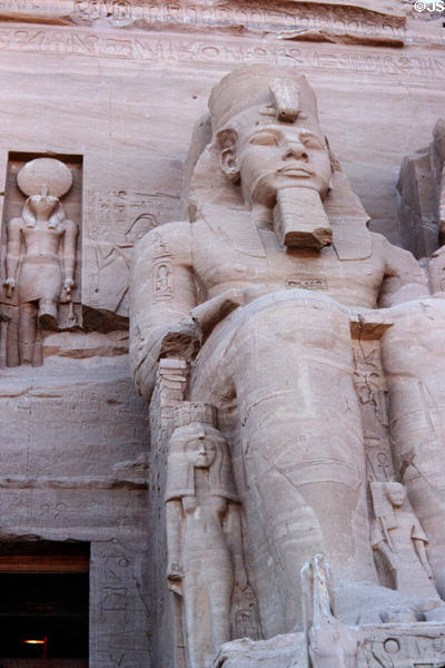 Carved Pharaoh with small scale wife on face of Great Temple of Ramesses II at Abu Simbel. Egypt.