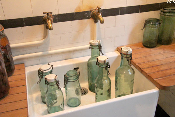 Preserve bottles in kitchen sink at Nissim de Camondo Museum. Paris, France.