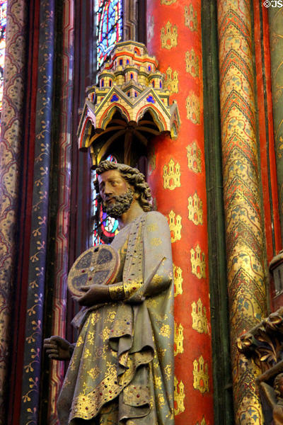 Carving of Saint with round cross on painted Gothic column at St Chapelle. Paris, France.