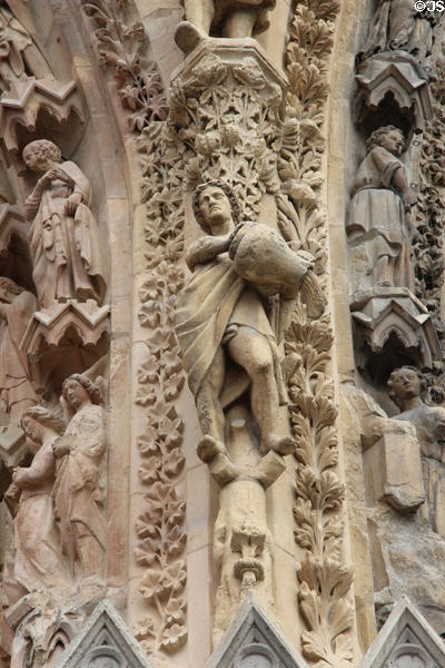 Detail of man pouring jug on portal carvings of Reims Cathedral. Reims, France.