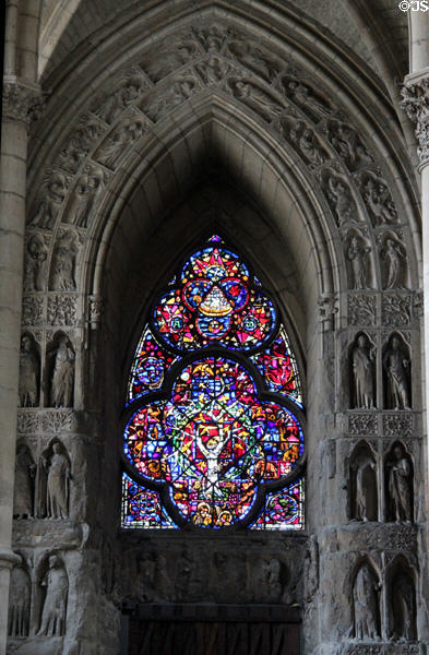 Stained glass window surrounded by niches with carved saints in Reims Cathedral. Reims, France.