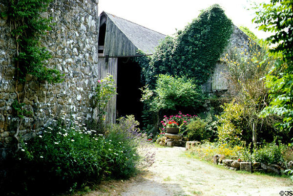 Old stone & wood Brittany farm buildings among flowers. Carnac, France.