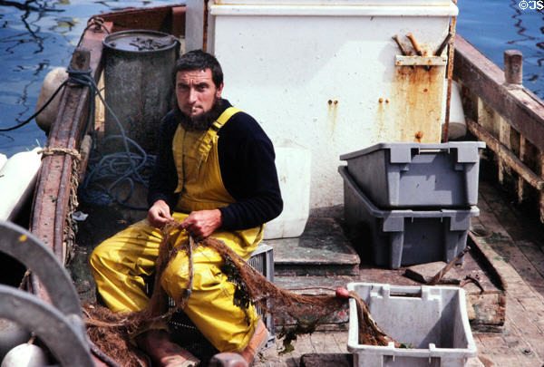 Fisherman mending a net on his boat. Belle-Isle-en-Mer, France.