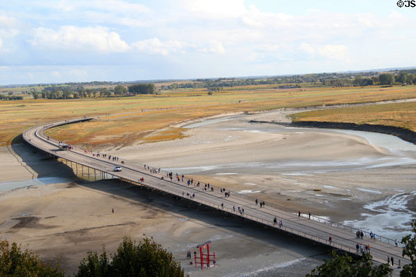 Visitors & mini-buses crossing bridge to & from mainland. Mont-St-Michel, France.