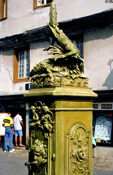 Elaborate iron water spigot topped by crocodile snagging fish, once used by townspeople as water source. Concarneau, France.
