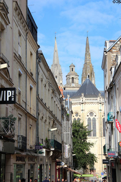 View of spires of St Maurice Cathedral over shops of rue Saint-Aubin. Angers, France.