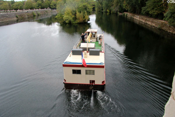 Tour boat on Cher River after passing under Gallery bridge of Chenonceau Chateau. Chenonceau, France.