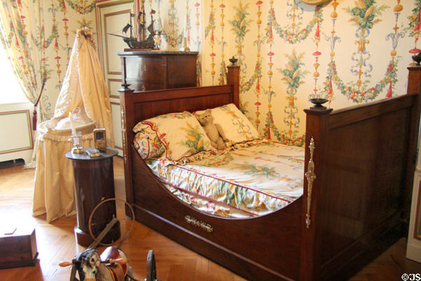 Empire-style bed in nursery with cradle beyond at Cheverny Chateau. Cheverny, France.