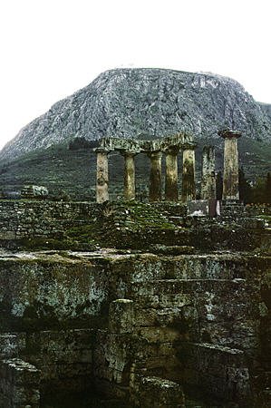 Temple of Apollo seen against Acrocorinth in Ancient Corinth. Greece.