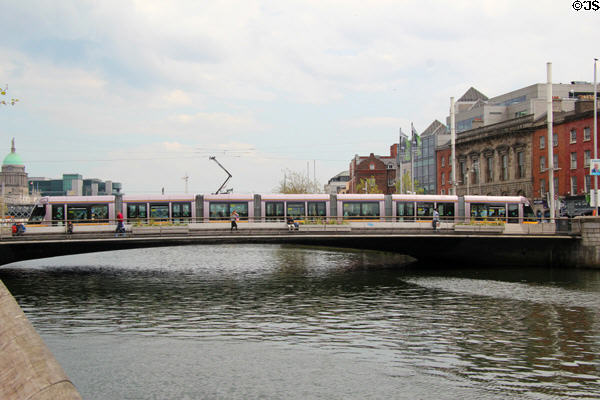 Tram crosses Rosie Hackett Bridge over River Liffey. Dublin, Ireland.