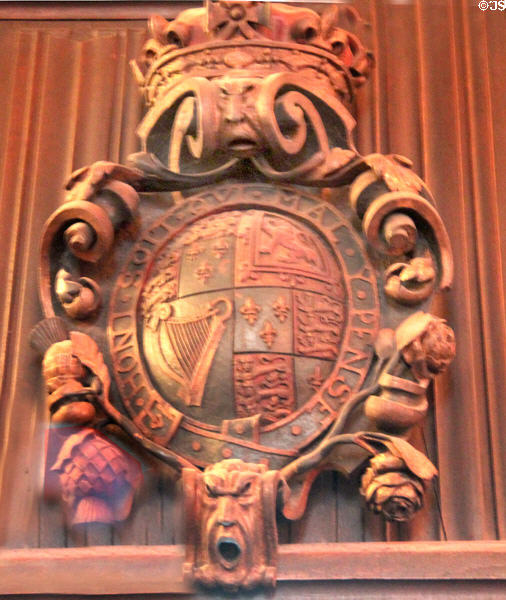Ornately carved wooden shield with the phrase "Honi Soit Qui Mal Y Pense, the motto of the Order of the Garter, a high British honor & symbols of the four nations comprising the UK at Bunratty Castle. County Clare, Ireland.