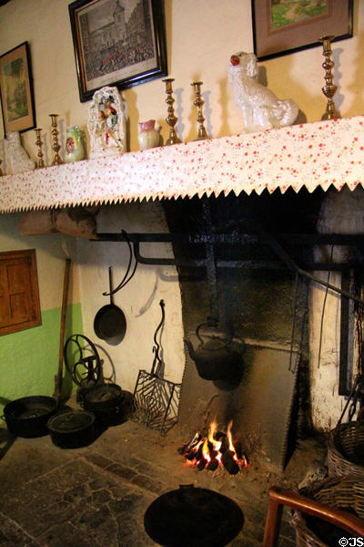 Open fireplace with mantel lined with decorative items in Golden Vale Farmhouse at Bunratty Castle & Folk Park. County Clare, Ireland.