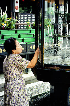 Woman lighting candles at the Nishi Otani Mausoleum, Kyoto. Japan.
