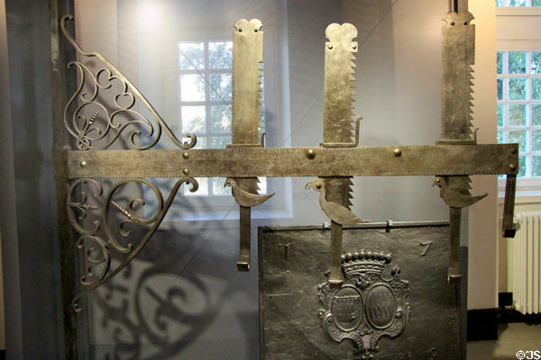 Pivoted pot hanger (1806) for fireplace cooking, with three adjustable height hooks decorated with birds at National Museum of History & Art. Luxembourg, Luxembourg.