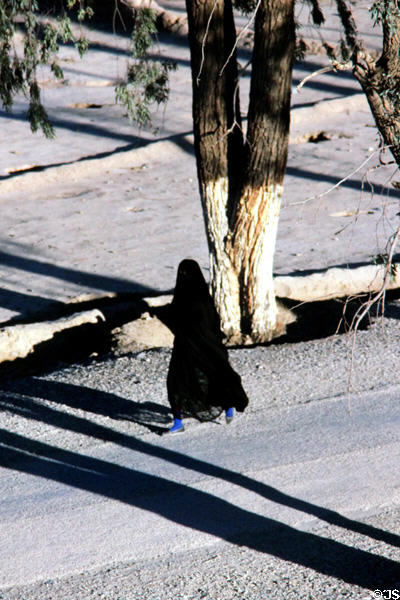 Woman walking on road. Erfoud, Morocco.