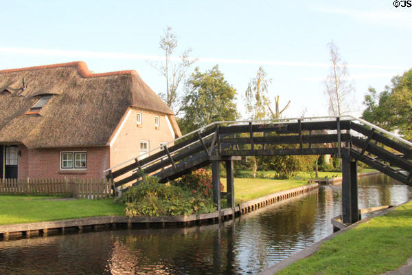 Pedestrian arched wooden bridge over canal. Giethoorn, Netherlands.