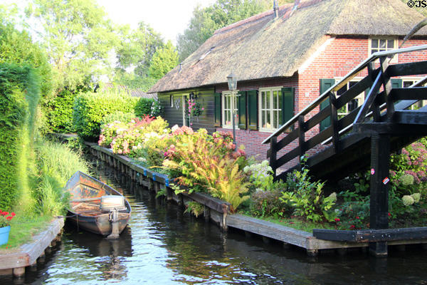 Narrow side canal with boat used for transportation around the town. Giethoorn, Netherlands.