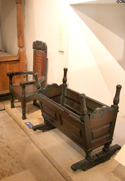 Oak armchair with coat of arms (1652) & cradle (17thC) from Linlithgow Palace both Scottish made at National Museum of Scotland. Edinburgh, Scotland.