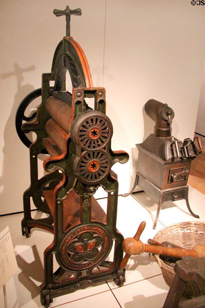 New Crown Jewel laundry mangle (1881) by Whitecross & Clark of Edinburgh beside stove with rack for heating irons at National Museum of Scotland. Edinburgh, Scotland.