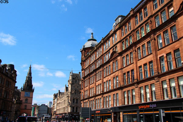 Red sandstone former City Improvement Trust. Block (1903-12) with octagonal corner tower with Tron Steeple beyond. Glasgow, Scotland. Architect: Thomson & Sandilands.